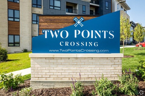 a sign for two points crossing in front of an apartment building